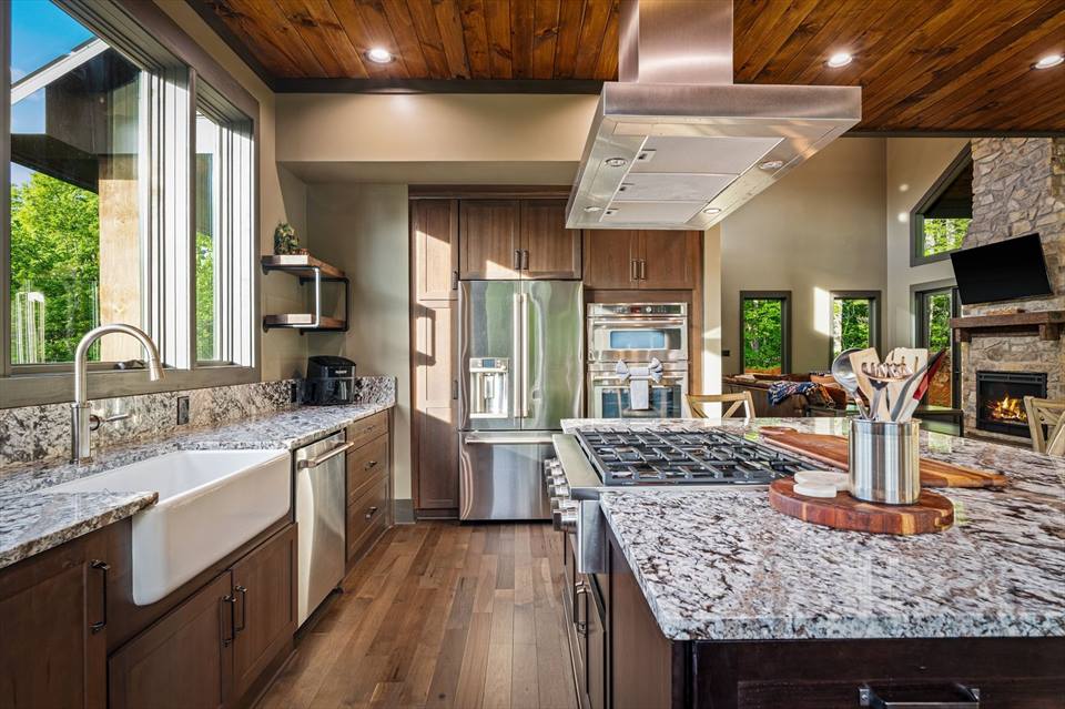 Chef's kitchen with granite island, wood cabinetry and farmhouse sink