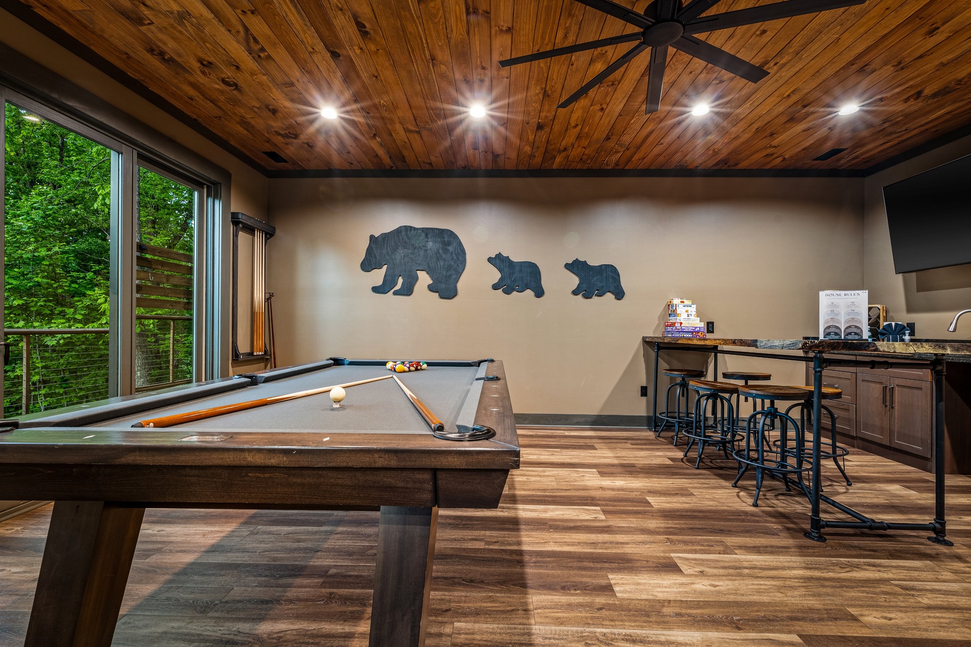 Game room with pool table, bar seating, forest and seasonal mountain views.