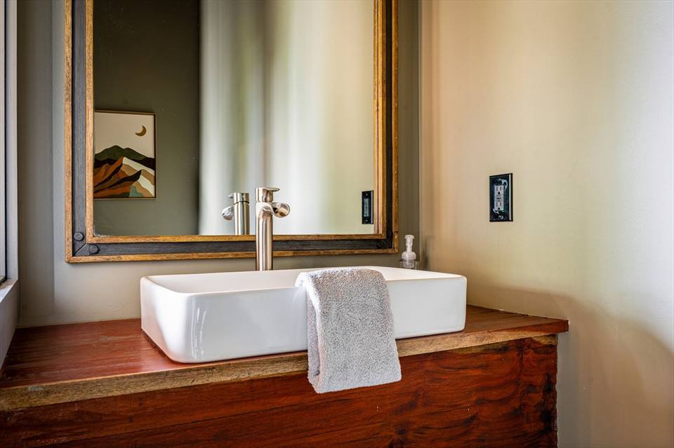 Main-floor half bath with vessel sink, wood vanity and framed mirror