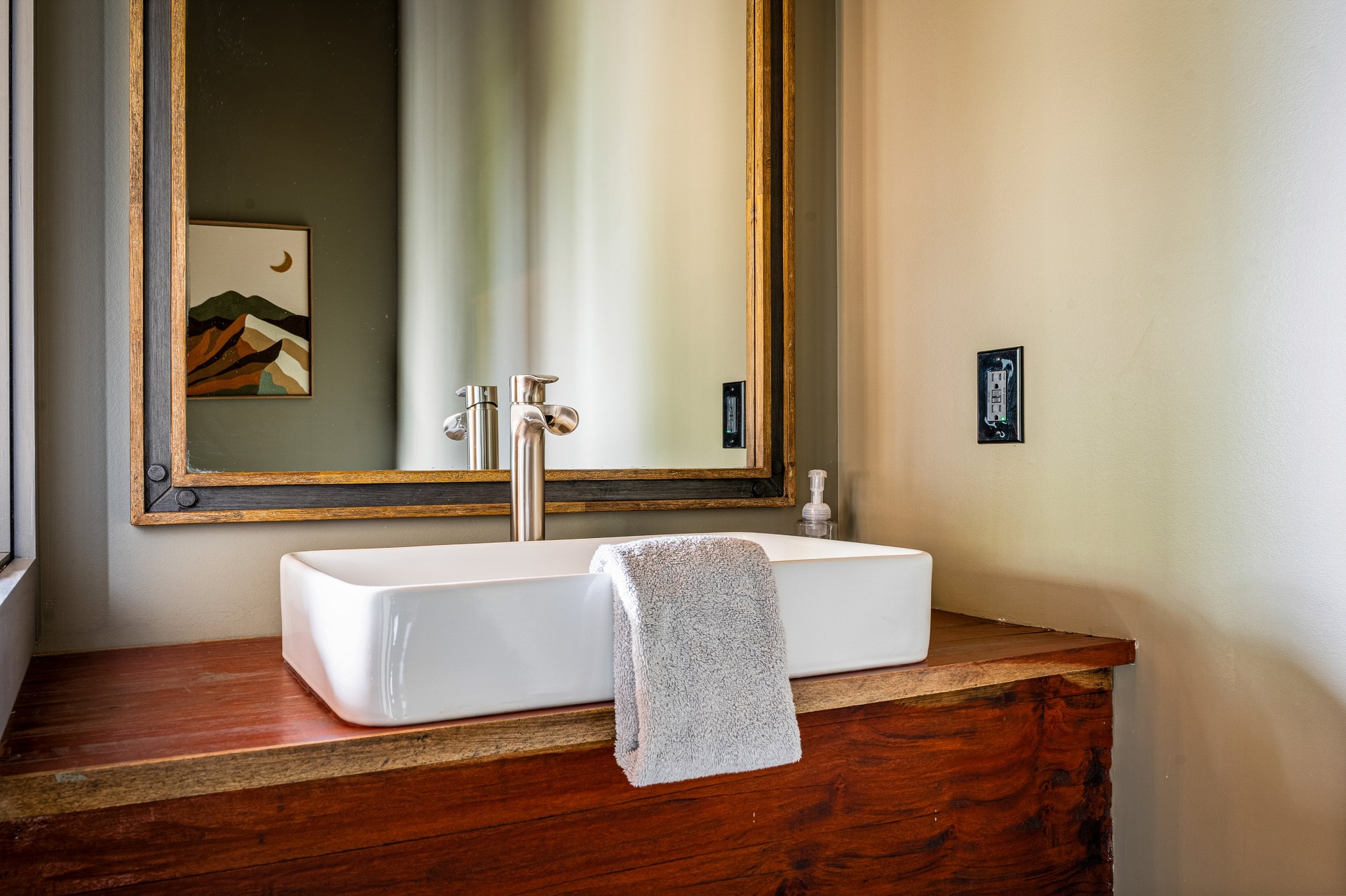 Main-floor half bath with vessel sink, wood vanity and framed mirror