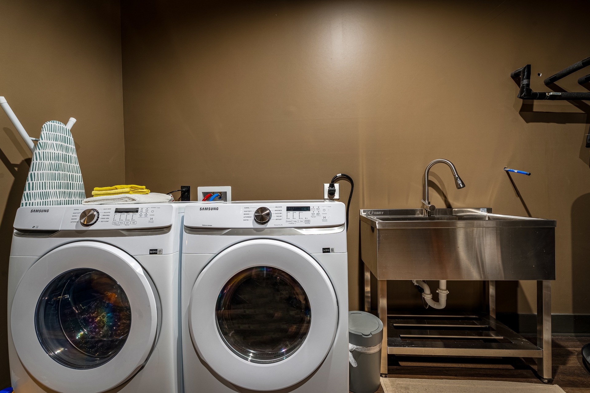In-unit laundry room with front-loading washer, dryer and utility sink