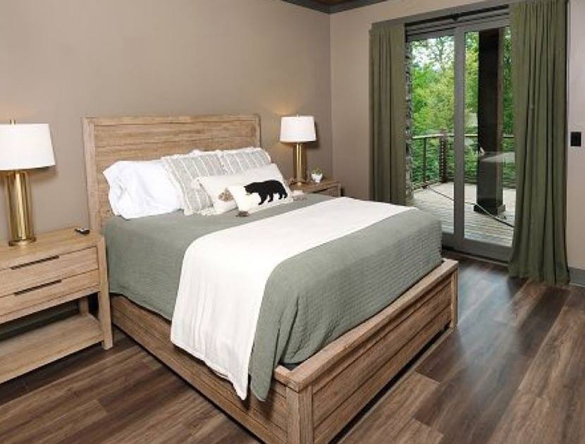 Bedroom 4's queen bed with bear pillow, nightstands and doors to the deck