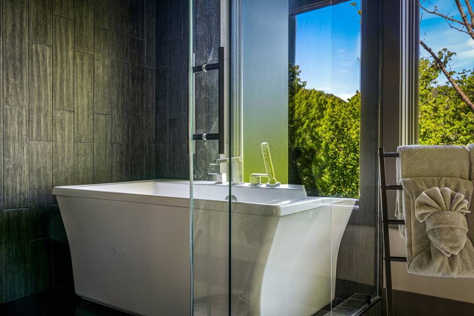 60-inch freestanding soaking tub by a forest-view window
